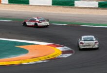 Two race cars navigate a sharp turn on a professional track, capturing the essence of motorsport speed.