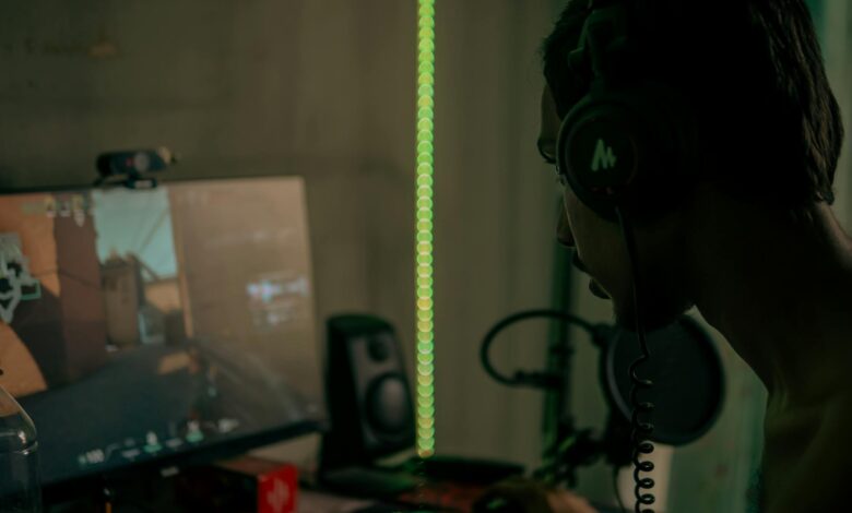 Focused gamer with headset playing a video game on a desktop computer indoors.
