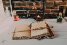 Magical close-up of a wand on an ancient spell book with potions.