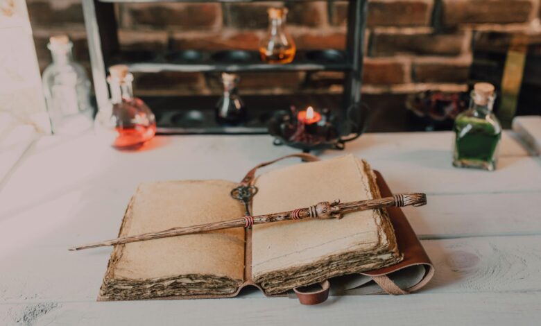 Magical close-up of a wand on an ancient spell book with potions.