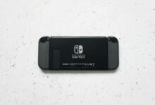 A close-up of a Nintendo Switch console placed on a textured marble surface, highlighting the device's sleek design.