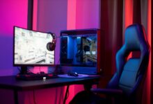 A sleek gaming setup featuring a high-end PC, widescreen monitor, and ergonomic chair lit by neon lights.