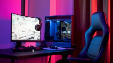 A sleek gaming setup featuring a high-end PC, widescreen monitor, and ergonomic chair lit by neon lights.