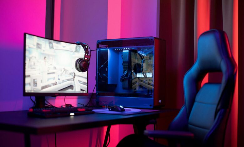 A sleek gaming setup featuring a high-end PC, widescreen monitor, and ergonomic chair lit by neon lights.