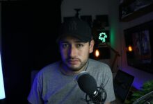 Male content creator in a home studio setup with microphone and soft lighting.
