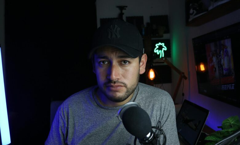 Male content creator in a home studio setup with microphone and soft lighting.