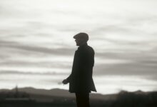 Silhouette of a man in a hat standing against a dramatic cloudy sky, conveying mystery and solitude.