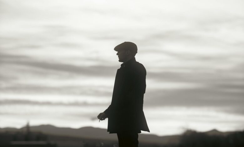 Silhouette of a man in a hat standing against a dramatic cloudy sky, conveying mystery and solitude.