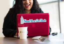 Young woman working remotely with a laptop in a modern indoor office setting, showcasing tech culture.