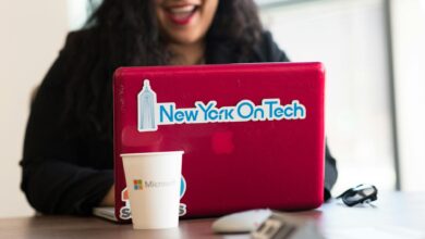 Young woman working remotely with a laptop in a modern indoor office setting, showcasing tech culture.