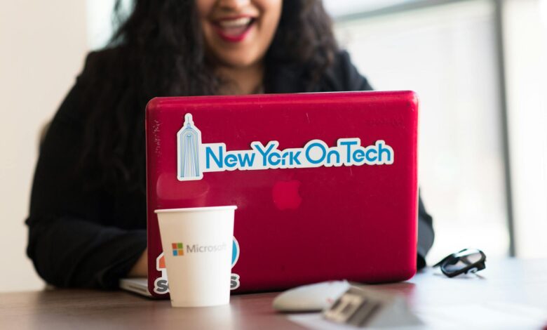 Young woman working remotely with a laptop in a modern indoor office setting, showcasing tech culture.