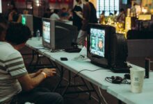 Adults enjoying a retro gaming event with CRT televisions and consoles, creating a nostalgic atmosphere indoors.