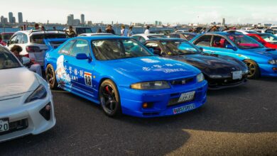 A lively outdoor car meet showcasing vibrant JDM sports cars under clear skies.