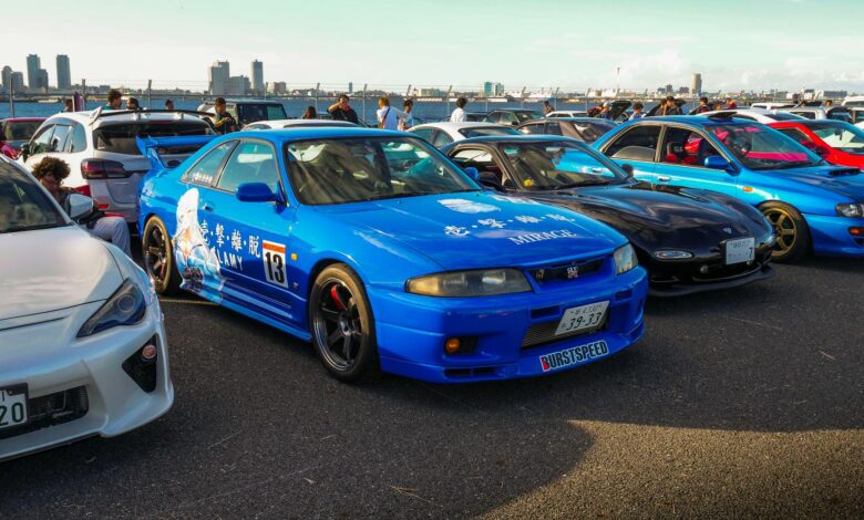 A lively outdoor car meet showcasing vibrant JDM sports cars under clear skies.