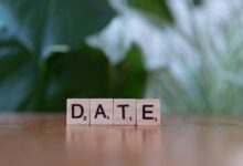 Wooden Scrabble tiles forming the word 'DATE' against a green blurred background.