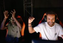 Two young men enthusiastically celebrate a win in an eSports tournament indoors.