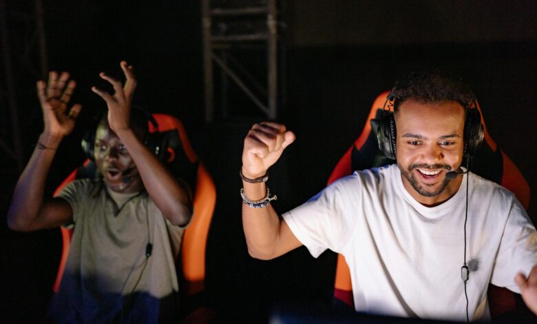 Two young men enthusiastically celebrate a win in an eSports tournament indoors.