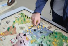 Close-up of a hand playing a strategic board game on a colorful map.