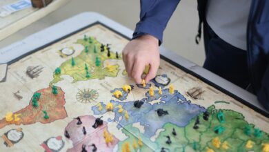 Close-up of a hand playing a strategic board game on a colorful map.