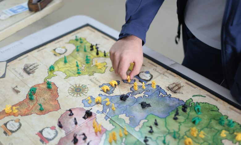 Close-up of a hand playing a strategic board game on a colorful map.