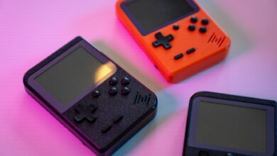 A vibrant still life of retro handheld game consoles in varying colors, set against a soft background.