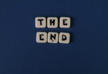 Scrabble tiles spelling 'The End' on a minimalist blue background. Perfect for conceptual designs.