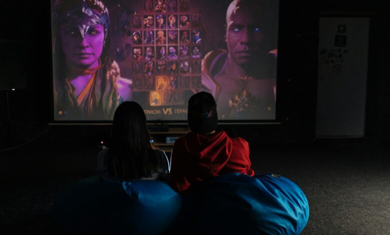 Two friends enjoying a video game session on a projector screen, immersed in gameplay.