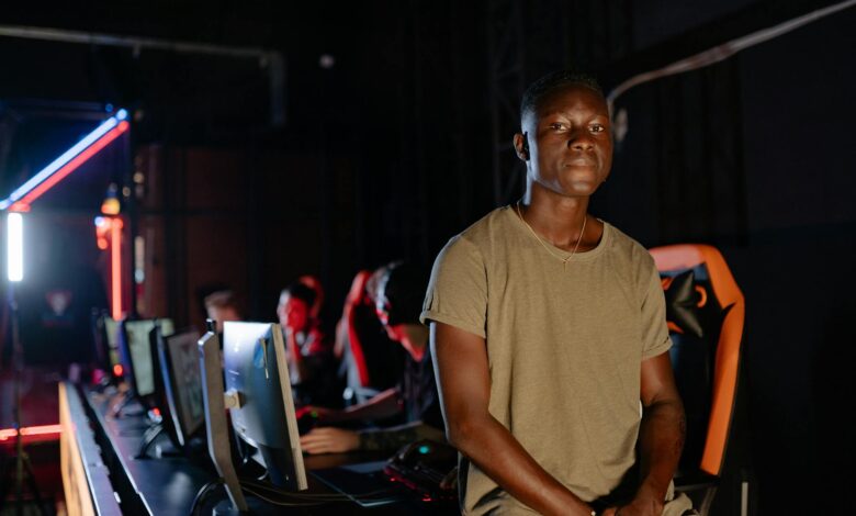 A young gamer in a dimly lit gaming arena, surrounded by teammates.