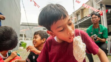 A boy competes in a traditional cracker eating contest during a festive outdoor event with friends.