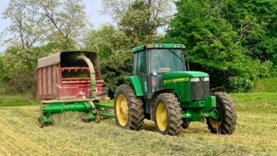Green tractor with hay wagon harvesting in Lancaster, PA during spring.