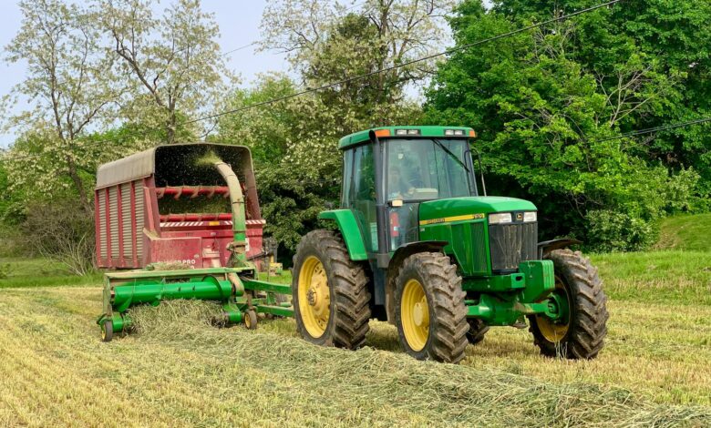 Green tractor with hay wagon harvesting in Lancaster, PA during spring.