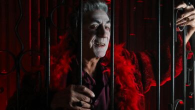 A spooky vampire in a red costume behind bars, perfect for Halloween and festive themes.