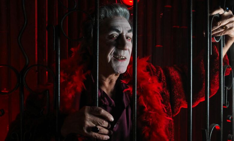 A spooky vampire in a red costume behind bars, perfect for Halloween and festive themes.