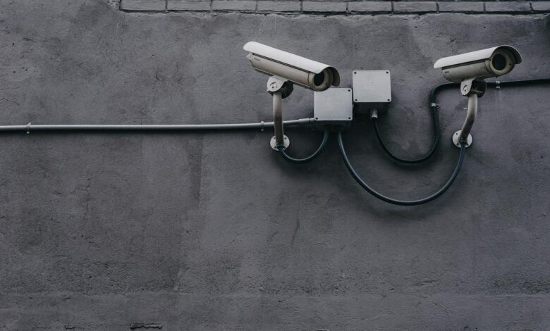 Two surveillance cameras mounted on a concrete wall, highlighting security technology.