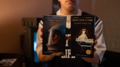 A person holding vintage VHS tapes in a cozy indoor setting.
