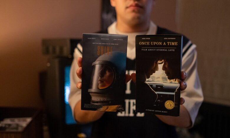 A person holding vintage VHS tapes in a cozy indoor setting.