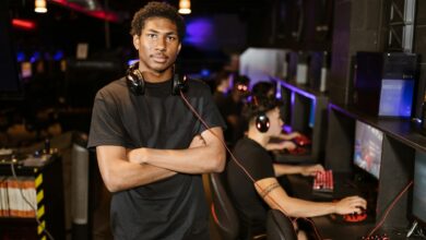Young gamer standing with arms crossed in an esports arena, exuding confidence.