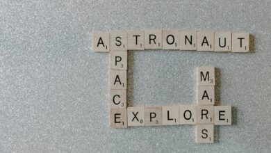 Wooden Scrabble tiles forming words related to space exploration on a glittery surface.