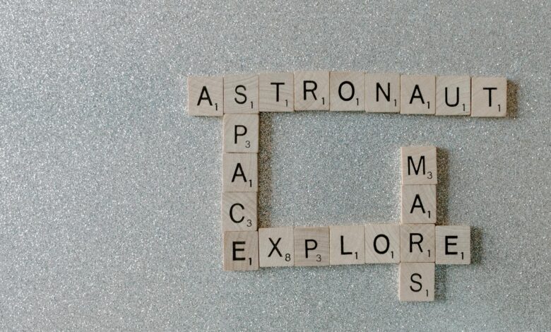 Wooden Scrabble tiles forming words related to space exploration on a glittery surface.