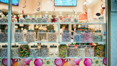 Vibrant candy shop window display with assorted colorful sweets in jars.
