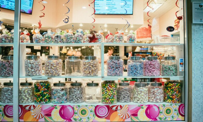 Vibrant candy shop window display with assorted colorful sweets in jars.