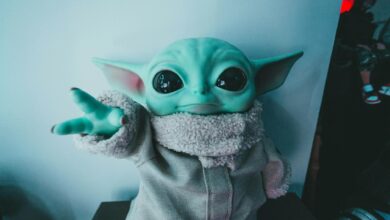 Cute Baby Yoda toy figurine in a cozy outfit reaching forward, perfect for fans.