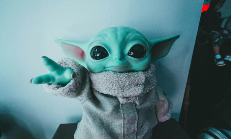 Cute Baby Yoda toy figurine in a cozy outfit reaching forward, perfect for fans.
