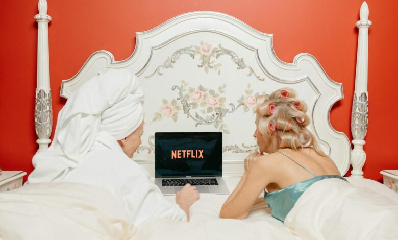 Two women enjoying Netflix in a cozy, vintage-style bedroom with red walls.
