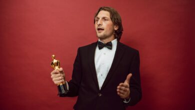 An accomplished man in a tuxedo holding a trophy, symbolizing triumph and recognition, against a red backdrop.