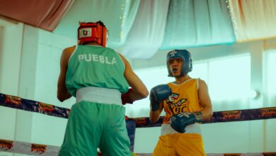 Two amateur boxers in colorful gear face off in an indoor ring.