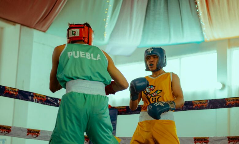Two amateur boxers in colorful gear face off in an indoor ring.
