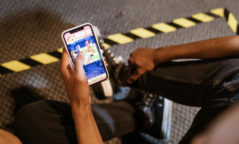 A person playing a colorful puzzle game on a smartphone while seated indoors.