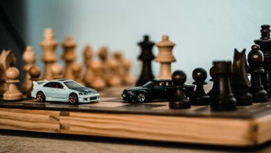 Model cars placed on a wooden chessboard, merging hobbies of model collecting and chess.