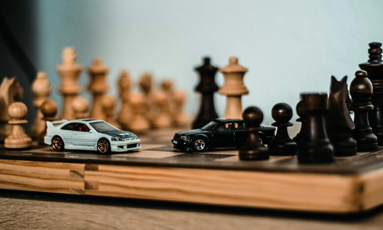 Model cars placed on a wooden chessboard, merging hobbies of model collecting and chess.